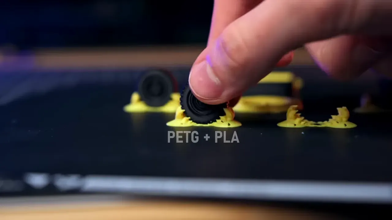 Support jaune imprimé sous une petite roue noire avec le texte PETG plus PLA